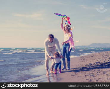 Family with little daughter resting and having fun with a kite at beach during autumn day. happy family enjoying vecation during autumn day