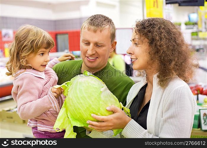 family with little girl buy cabbage in supermarket