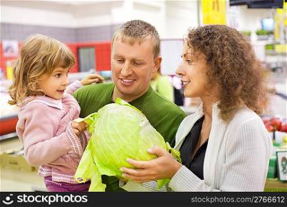 family with little girl buy cabbage in supermarket