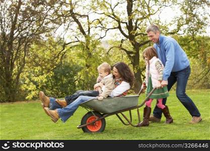 Family With Man Giving Mother And Children Ride In Wheelbarrow