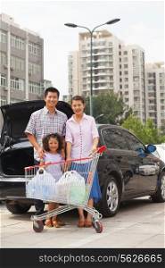 Family with shopping cart standing next to the car