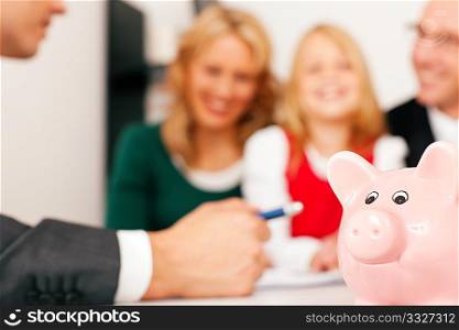 Family with their consultant (assets, money or similar) doing some financial planning - symbolized by a piggy bank in the front (focus only on piggy bank!)
