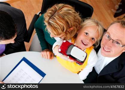 Family with their consultant (assets, money or similar) doing some financial planning - symbolized by a toy car they are holding in their hand