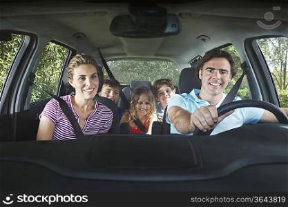 Family with three children (5-11) in car interior, portrait