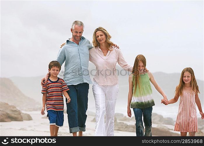 Family with three children (5-6 7-9 10-12) walking on beach