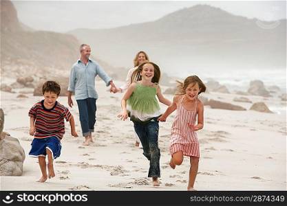 Family with three children (5-6 7-9 10-12) walking on beach