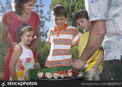 Family with three children (6-11) grilling in garden