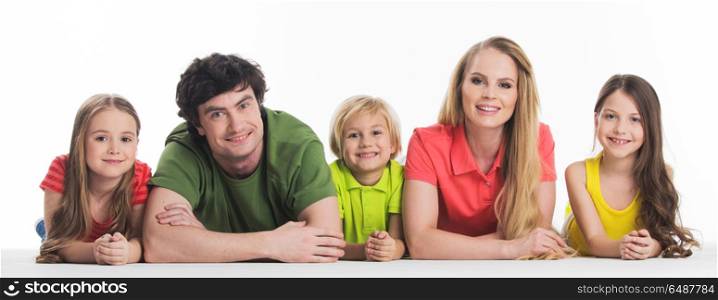 Family with three children. Happy smiling family of two parents and three children lying on the floor studio isolated on white background