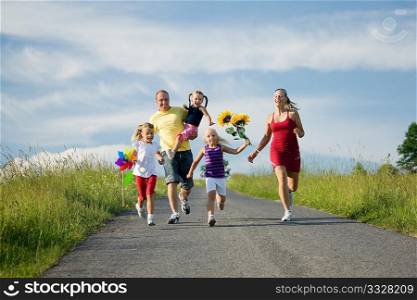 Family with three kids running down a hill