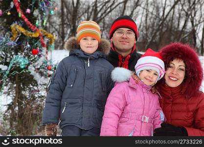 family with two children: father, mother, boy and girl near christmass tree.