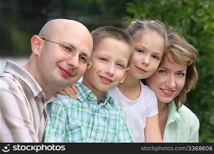 family with two children in early fall park near pond. focus on little boy&acute;s face.