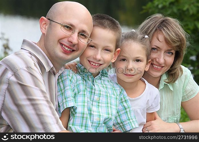 family with two children in park near pond. focus on little girl&acute;s face.