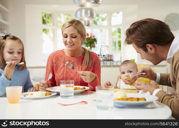 Family With Young Baby Eating Meal At Home