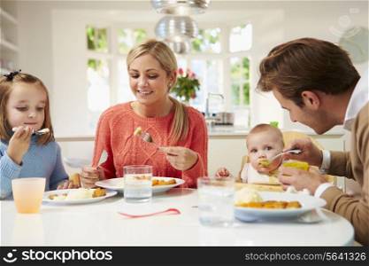Family With Young Baby Eating Meal At Home