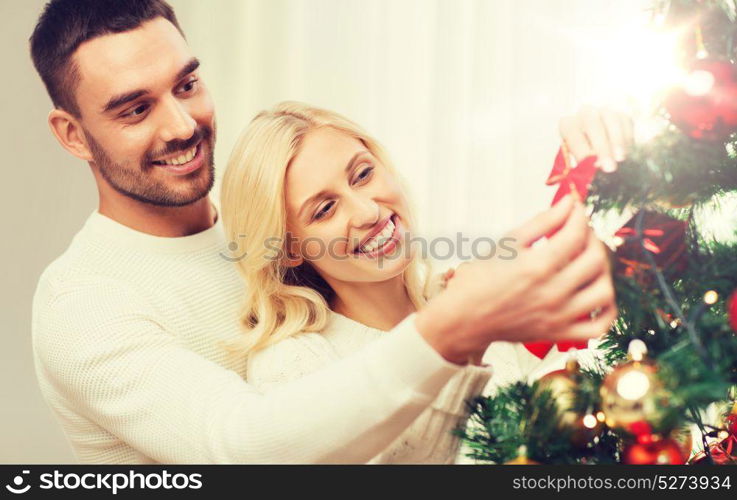 family, x-mas, winter holidays and people concept - happy couple decorating christmas tree at home. happy couple decorating christmas tree at home