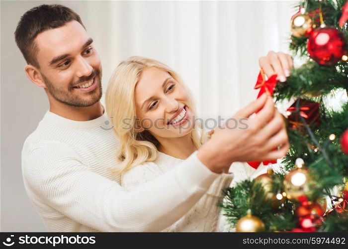family, x-mas, winter holidays and people concept - happy couple decorating christmas tree at home