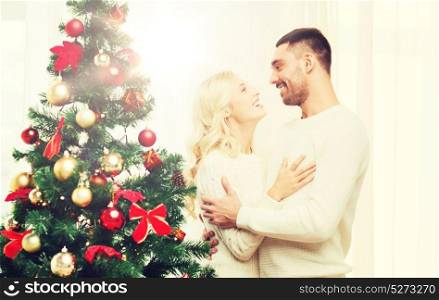 family, x-mas, winter holidays and people concept - happy couple hugging near christmas tree at home. happy couple hugging near christmas tree at home