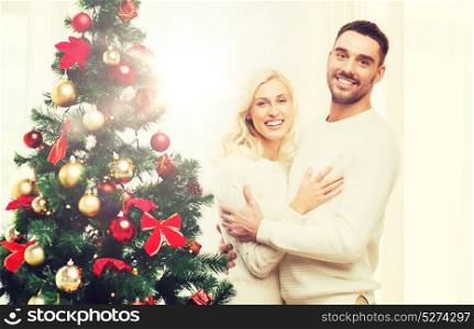 family, x-mas, winter holidays and people concept - happy couple hugging near christmas tree at home. happy couple hugging near christmas tree at home