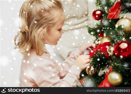 family, x-mas, winter holidays and people concept - happy little girl decorating christmas tree with mother at home