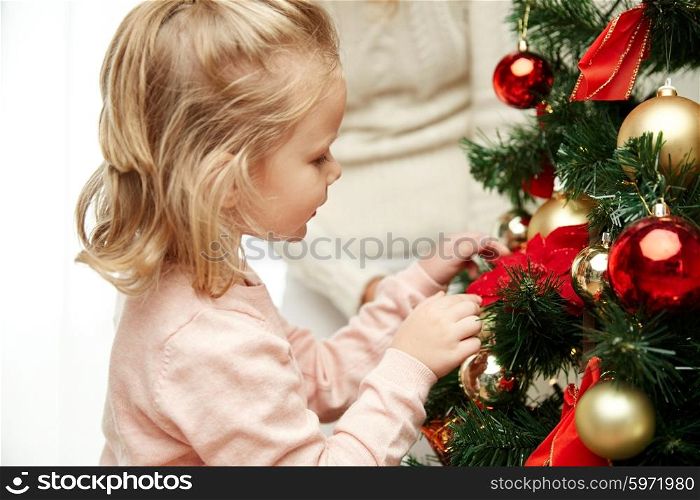 family, x-mas, winter holidays and people concept - happy little girl decorating christmas tree with mother at home