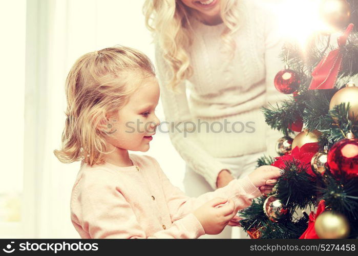 family, x-mas, winter holidays and people concept - happy mother and little daughter decorating christmas tree at home. happy family decorating christmas tree at home