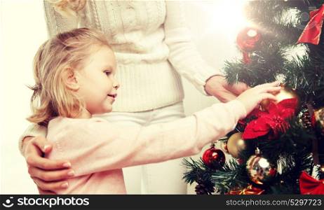 family, x-mas, winter holidays and people concept - happy mother and little daughter decorating christmas tree at home. happy family decorating christmas tree at home