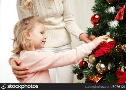 family, x-mas, winter holidays and people concept - happy mother and little daughter decorating christmas tree at home