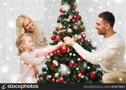 family, x-mas, winter holidays and people concept - happy mother, father and little daughter decorating christmas tree at home