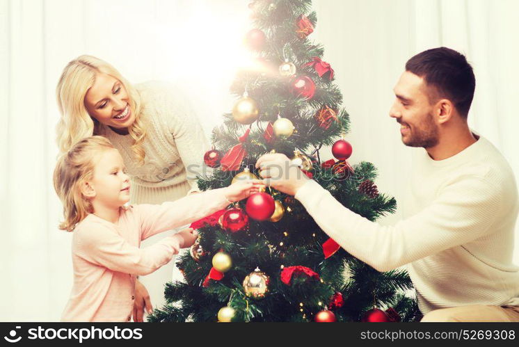 family, x-mas, winter holidays and people concept - happy mother, father and little daughter decorating christmas tree at home. happy family decorating christmas tree at home