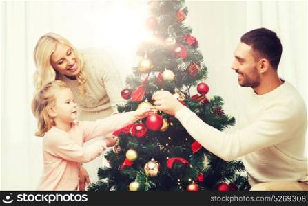 family, x-mas, winter holidays and people concept - happy mother, father and little daughter decorating christmas tree at home. happy family decorating christmas tree at home