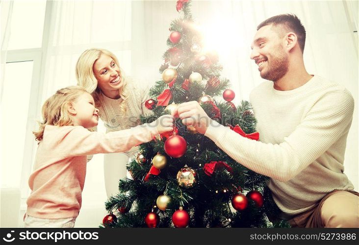 family, x-mas, winter holidays and people concept - happy mother, father and little daughter decorating christmas tree at home. happy family decorating christmas tree at home