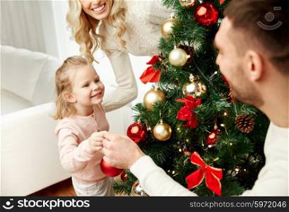 family, x-mas, winter holidays and people concept - happy mother, father and little daughter decorating christmas tree at home