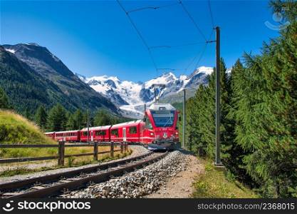 Famous Bernina tourist train passing under the glaciers of the Swiss Alps