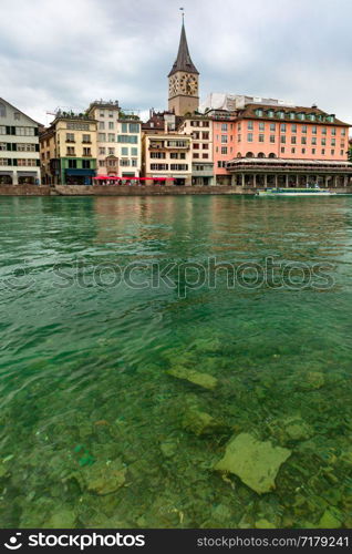 Famous Church of St Peter and river Limmat on the cloudy day in Old Town of Zurich, the largest city in Switzerland. Zurich, largest city in Switzerland