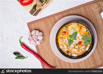 famous delicious Thai Tom yum spicy soup with champignon on bamboo napkin. served on white table. flat lay