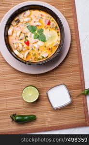 famous delicious Thai Tom yum spicy soup with champignon on bamboo napkin. served on white table. flat lay