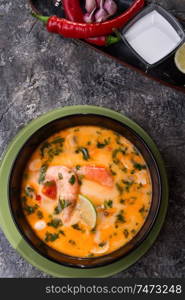 famous delicious Thai Tom yum spicy soup with shrimps and coconut milk on black table. close up. flat lay