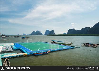 Famous floating football or soccer field at panyee island with float house and limestone mountains, Phang Nga bay, Thailand. Here is Muslim people, immigrate from Indonesia, live surround shallow sea