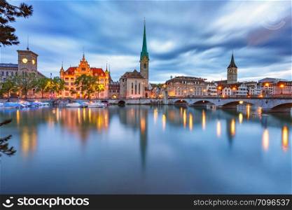 Famous Fraumunster and Church of St Peter with their reflections in river Limmat during morning blue hour in Old Town of Zurich, the largest city in Switzerland. Zurich, the largest city in Switzerland