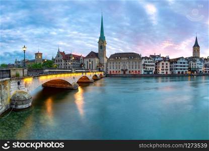 Famous Fraumunster church and Munsterbrucke bridge over river Limmat at sunset in Old Town of Zurich, the largest city in Switzerland. Zurich, largest city in Switzerland