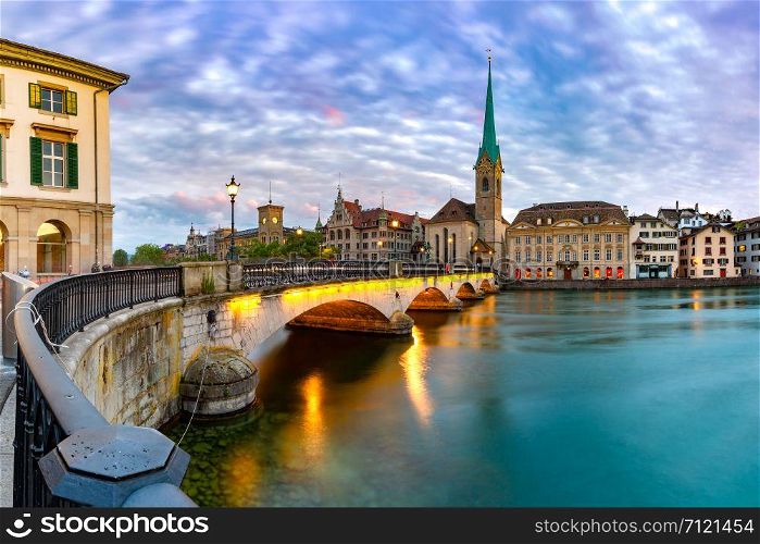 Famous Fraumunster church and Munsterbrucke bridge over river Limmat at sunset in Old Town of Zurich, the largest city in Switzerland. Zurich, largest city in Switzerland