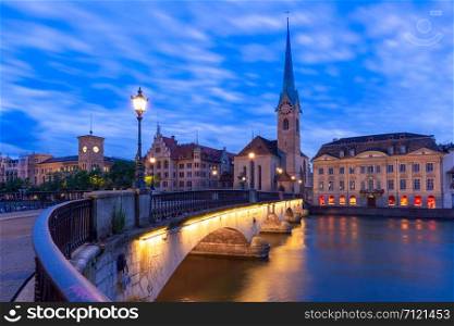Famous Fraumunster church and Munsterbrucke bridge over river Limmat during evening blue hour in Old Town of Zurich, the largest city in Switzerland. Zurich, largest city in Switzerland
