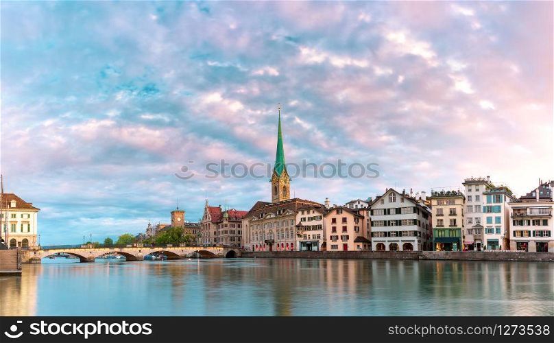 Famous Fraumunster church with its reflections in river Limmat at pink sunrise in Old Town of Zurich, the largest city in Switzerland. Zurich, largest city in Switzerland