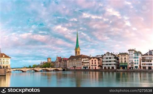 Famous Fraumunster church with its reflections in river Limmat at pink sunrise in Old Town of Zurich, the largest city in Switzerland. Zurich, largest city in Switzerland