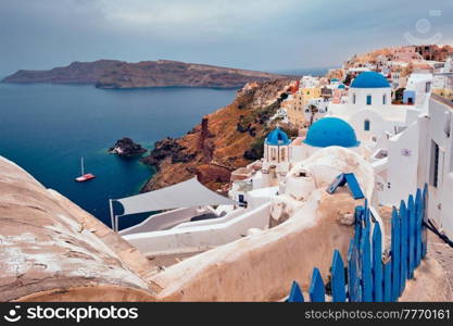 Famous greek iconic selfie spot tourist destination Oia village with traditional white houses and church in Santorini island on sunset in twilight, Greece. Famous greek tourist destination Oia, Greece