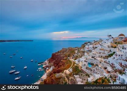 Famous greek iconic selfie spot tourist destination Oia village with traditional white houses and windmills in Santorini island on sunset in twilight, Greece. Famous greek tourist destination Oia, Greece