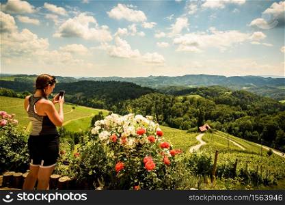 Famous Heart shaped wine road in Slovenia in summer, woman with a mobile phone photographing heart. Heart form - Herzerl Strasse, vineyards in summer, Spicnik. Herzerl Strasse, vineyards in summer, Spicnik