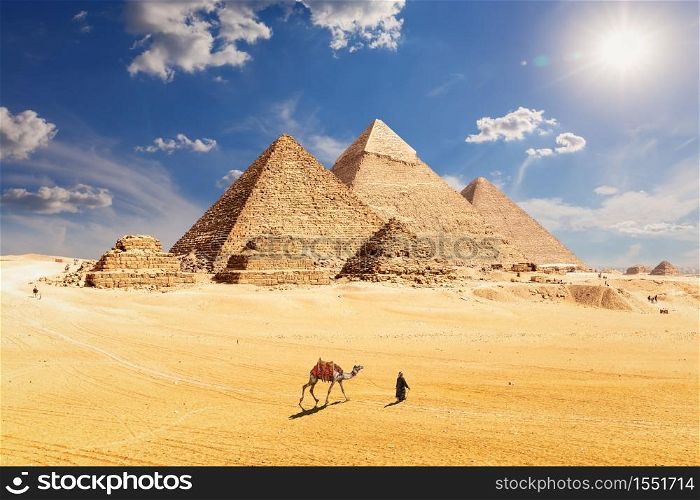 Famous Pyramids of Egypt and a bedouin with a camel, Giza, Cairo.