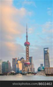 Famous Shanghai tv tower and city skyline in susnet light with cloudy sky on background, China