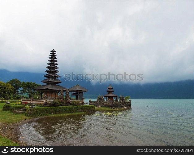 Famous temple near Gunung Batur volcano on lake Bratan with low clouds above it